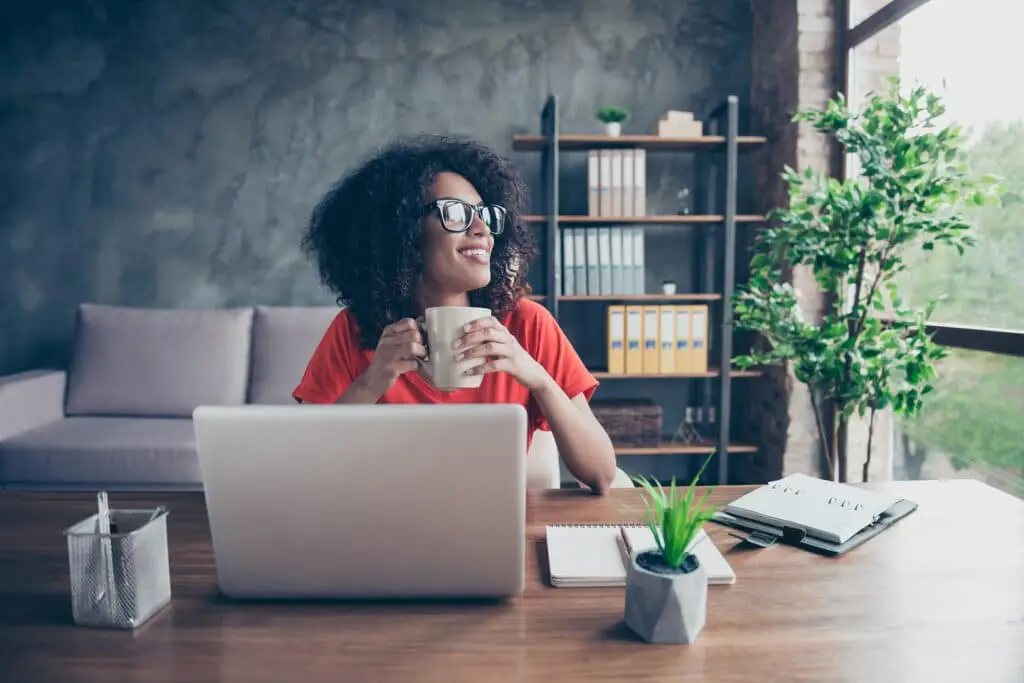 Navigating Cybersecurity Challenges While Working Remotely 3 young woman in a cozy workspace enjoys coffee amidst sunlight, plants, and creativity.