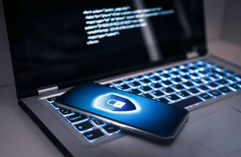 Getting Employees To Engage In Cybersecurity 1 smartphone with lock symbol on laptop, highlighting essential cybersecurity measures against digital threats.