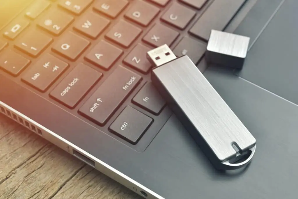 What'S So Bad About Usb Drives? 1 sleek metal usb drive connected to laptop, showcasing modern data transfer on wood desk.