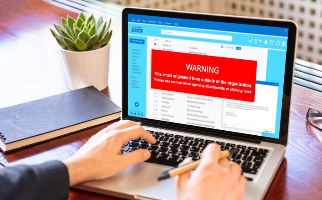 cybersecurity warning on laptop about email attachments, highlighting risks like malware and phishing.