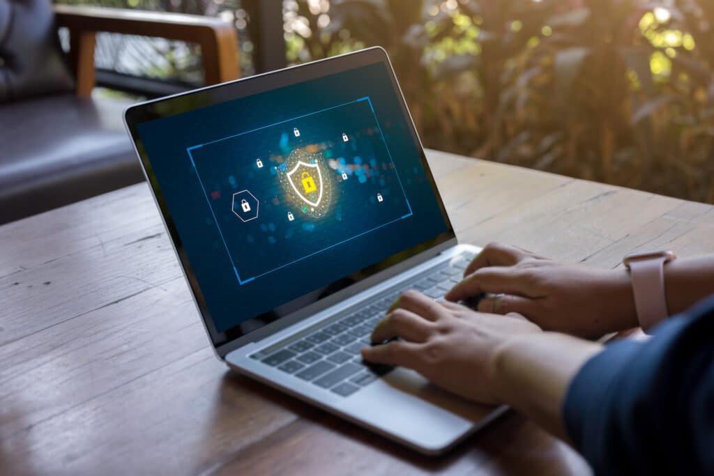 person using a laptop, emphasizing cybersecurity and online safety with a digital shield display.